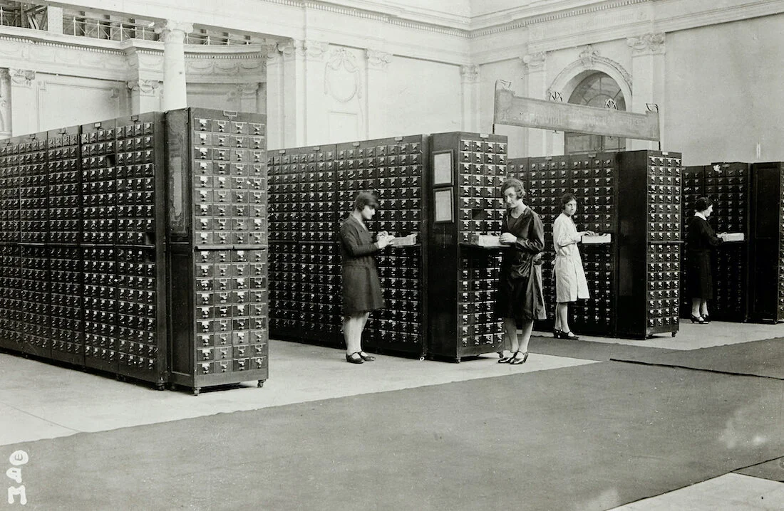 Photographie du Répertoire Bibliographique Universel, installé au Palais du Cinquantenaire à Bruxelles, avec des collaboratrices y travaillant
